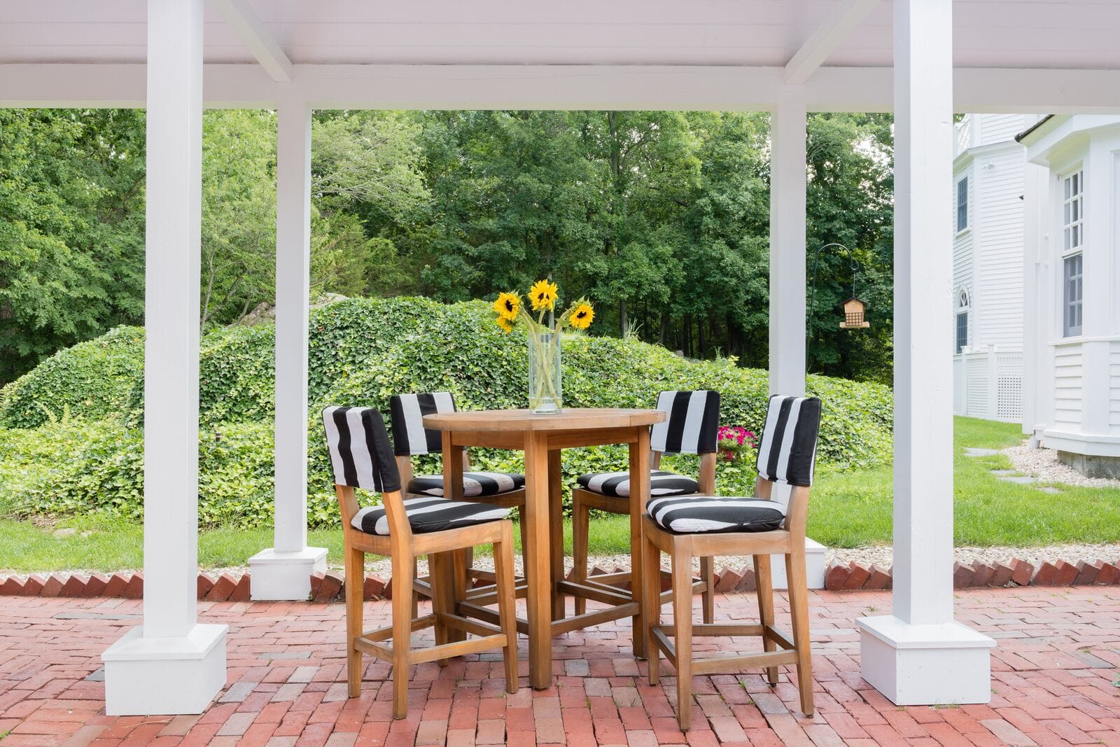 wooden hightop table and chairs under covered porch