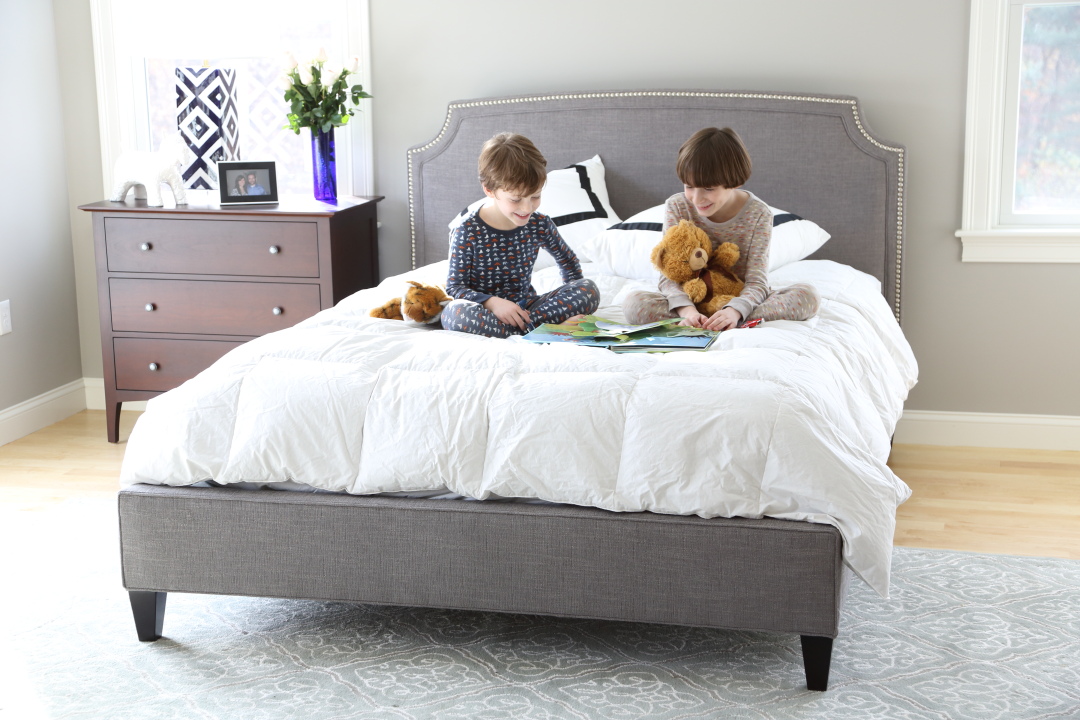 two kids sitting on bed with books and stuffed animals