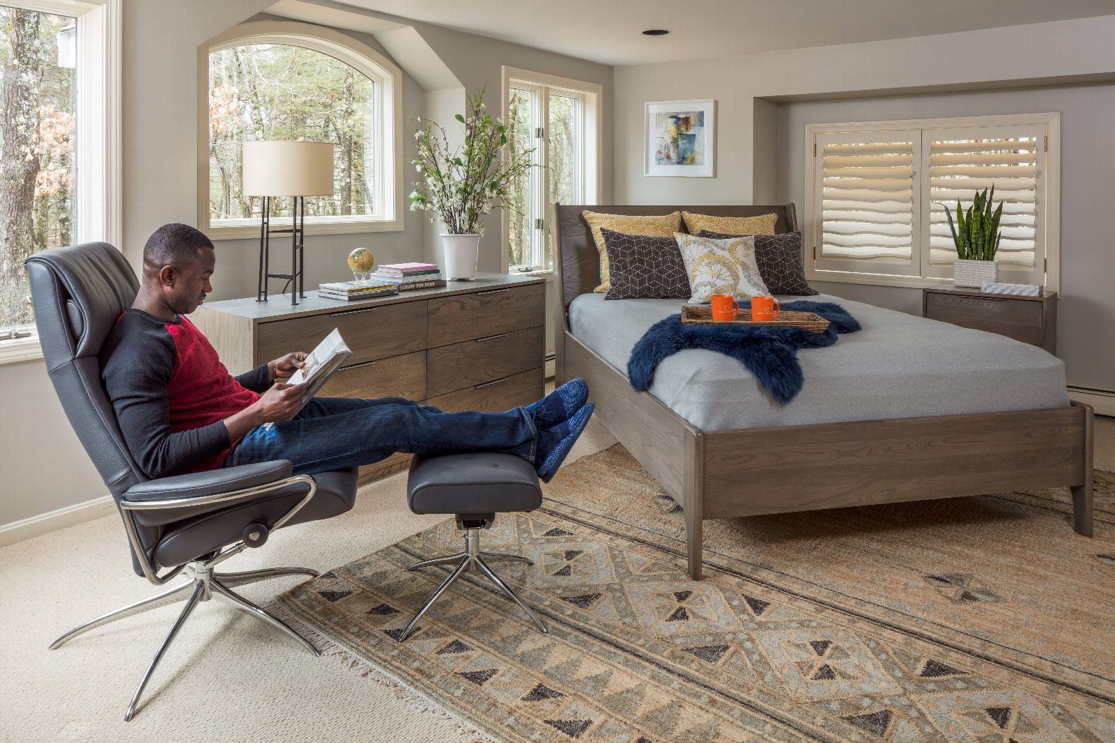 man reading newspaper in chair in bedroom