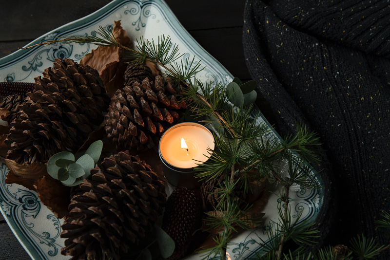 candle with pinecones and pine needles surrounding it