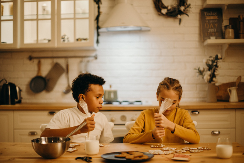 two children decorating cookies in a kitchen